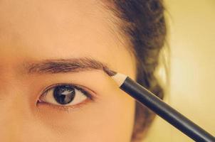 rostro de belleza de mujer asiática aplicando lápiz de cejas sobre la piel. foto