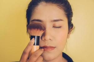Beauty face of Asian woman by applying brushes on skin by cosmetics.