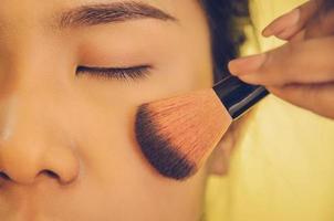 rostro de belleza de mujer asiática mediante la aplicación de pinceles en la piel con cosméticos. foto