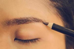 rostro de belleza de mujer asiática aplicando lápiz de cejas sobre la piel. foto