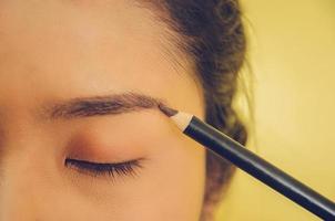 rostro de belleza de mujer asiática aplicando lápiz de cejas sobre la piel.