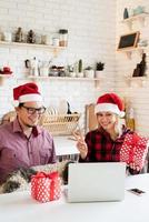 Couple in santa hats greeting their friends in a video call photo
