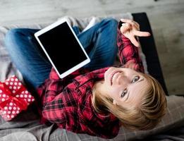 Young blonde woman in working on tablet sitting on the couch, top view photo