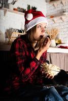 Woman watching movies at home at Christmas night eating popcorn photo