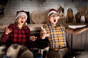 Couple watching movies at home at Christmas pointing to the screen photo