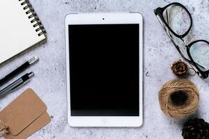 Tablet, glasses, label and stationery on cement floor photo