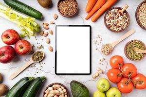 Top view of a tablet with white screen for mock up with healthy foods photo