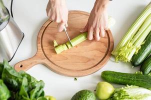 High angle view of female hands cutting celery photo