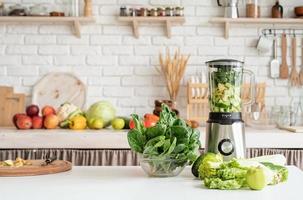 Home kitchen with a table with green vegetables and blender photo