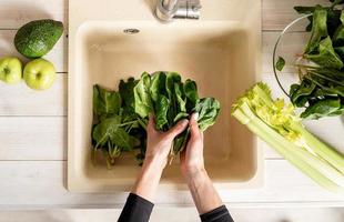 Top view of woman hands washing spinach at kitchen sink photo