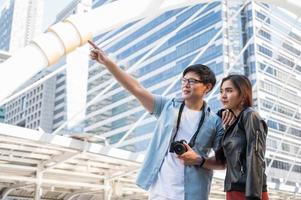 pareja asiática turista mirando y señalando con el dedo hacia adelante foto