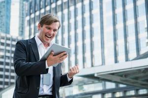 Young business man feeling happy holding tablet