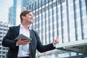 Young business man feeling happy holding tablet