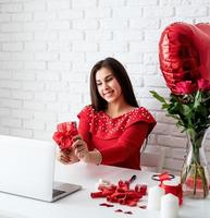 Woman dating online holding a present over white brick wall background photo