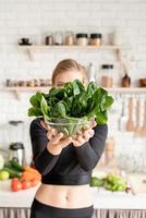 Mujer sosteniendo un plato de espinacas frescas en la cocina foto