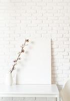 Mock up poster frame with cotton branch on white brick wall background