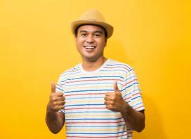 Joven asiático con sombrero se siente feliz y sorpresa mostrando el pulgar hacia arriba foto