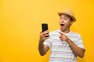 Asian man happy with his smartphone on yellow background. photo