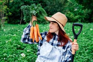 mujer sosteniendo zanahorias y pala foto