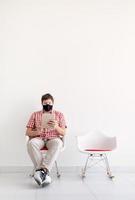 Joven en máscara protectora estudiando en línea manteniendo la distancia social foto
