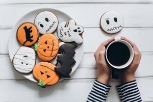 Female preparing for Halloween, drinking coffee with gingerbread photo