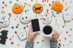 A preparation for Halloween. Female holding coffee and smartphone. photo