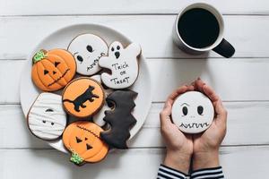 Female preparing for Halloween, drinking coffee with gingerbread photo