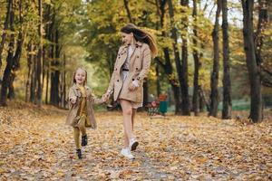 madre y su hija se divierten y caminan en el parque de otoño. foto