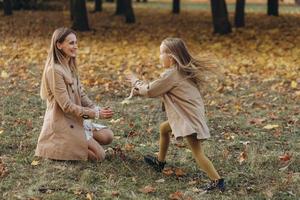 madre y su hija se divierten y caminan en el parque de otoño.