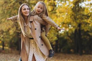 Mother and her daughter have fun and walk in the autumn park. photo