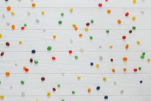Many multicolored sweet candies on white wooden background. photo