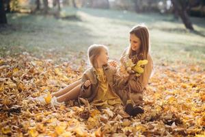 madre e hija sentadas y divirtiéndose en el parque de otoño. foto