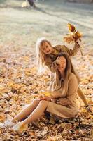 madre e hija sentadas y divirtiéndose en el parque de otoño. foto