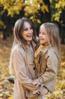 madre y su hija se divierten y caminan en el parque de otoño. foto