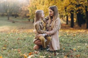 madre y su hija se divierten y caminan en el parque de otoño. foto