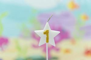 Lighted birthday candle in star shape with blurred background photo