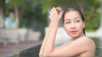 une jeune femme asiatique profite d'une piscine extérieure video