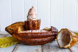 Fresh cocoa pods and cocoa leaves on wooden background photo