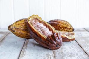 Fresh cocoa pods and cocoa leaves on wooden background photo