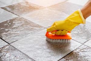 Using a plastic floor scrubber to scrub the tile floor. photo