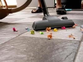 Sweep up paper scraps and dust on tile floors with a vacuum cleaner. photo