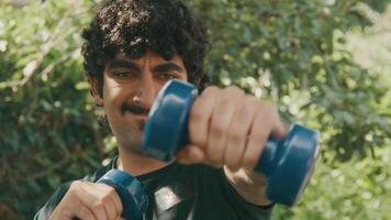 Homme debout dans le jardin faisant des mouvements de boxe avec des haltères video