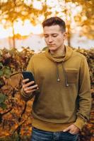 Happy guy smiling and talking on the phone in the autumn park photo