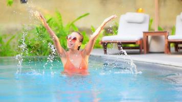 mujer joven disfruta alrededor de la piscina al aire libre video