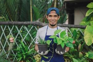 Hombre asiático feliz vender jardín de plantas en la tienda foto