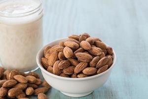 Cerrar almendras y vaso de leche de almendras foto