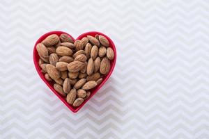 Merienda de almendras en un tazón de corazón rojo foto