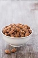 White Bowl of Almonds on Wood Background photo