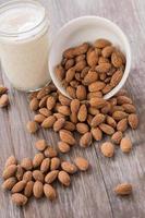 White Bowl With Almonds Spilling and Glass of Almond Milk photo