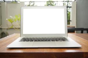 Laptop with blank screen on wooden table in front of library photo